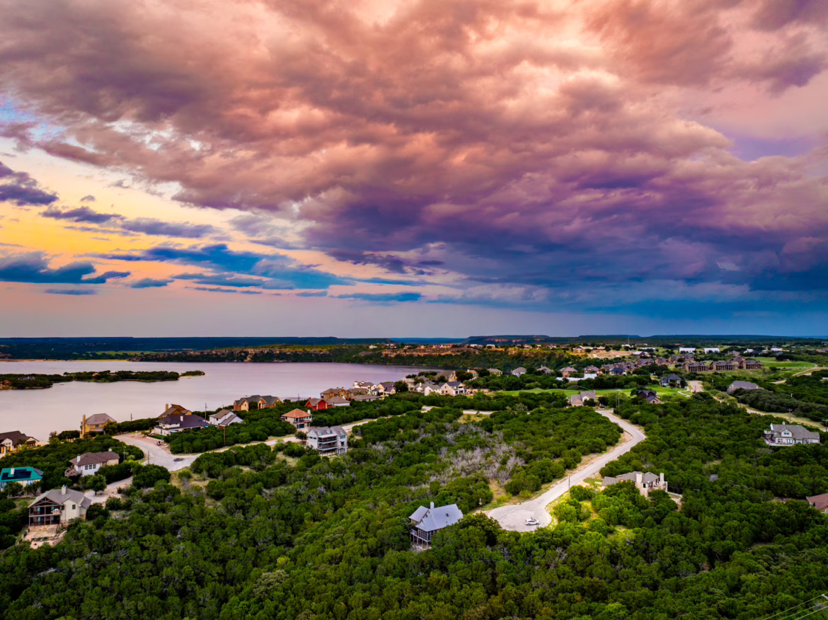 Aerial drone view of vacant lots in The Cliffs at Possum Kingdom Lake with sunset and lake in the distance